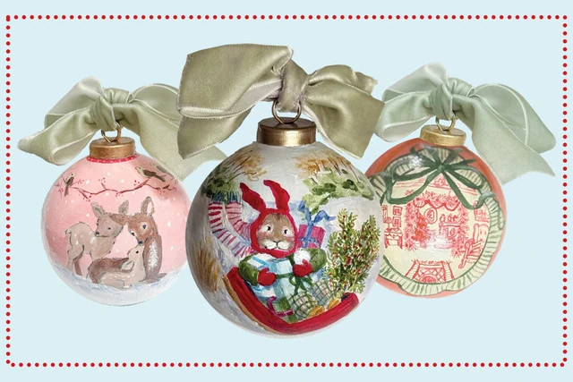 Three hand painted ceramic holiday ornaments decorated with seasonal illustrations and ribbon bows